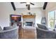 Bright living area features stone fireplace, hardwood floors, and dark stained wooden ceiling beams at 209 Wynnward Way, Sharpsburg, GA 30277