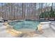 A beautiful in-ground pool with stone accents and surrounding trees, creating a private and relaxing outdoor space at 209 Wynnward Way, Sharpsburg, GA 30277