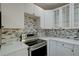 A close view of a stainless steel oven and stovetop, plus white cabinets and gray backsplash at 3680 Larkspur Ter, Decatur, GA 30032