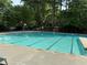 The community pool features marked lanes, concrete, and stone, with chairs and a wooded area behind it at 143 Lablanc Nw Way, Atlanta, GA 30327