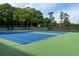Well-maintained tennis courts with blue surface and green trim surrounded by mature trees under a sunny sky at 143 Lablanc Nw Way, Atlanta, GA 30327