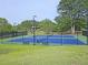 Well-maintained blue tennis courts surrounded by green grass and trees within the community at 143 Lablanc Nw Way, Atlanta, GA 30327
