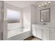 Bathroom with white cabinets, double sinks, tub/shower, and a large window at 553 Princeton Elm Place Way, Lawrenceville, GA 30045