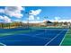 Outdoor tennis courts with blue playing surface and lights, surrounded by trees and community buildings at 553 Princeton Elm Place Way, Lawrenceville, GA 30045