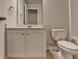 Bathroom features a single vanity with gray counter and white cabinets next to the toilet at 6468 Pierless Ave, Sugar Hill, GA 30518