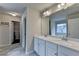 Bathroom with double sink vanity, large mirror, and a door that leads to the walk in closet at 6468 Pierless Ave, Sugar Hill, GA 30518