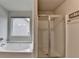 Bathroom featuring a soaking tub under a window and a glass enclosed shower with a towel rack at 6468 Pierless Ave, Sugar Hill, GA 30518