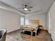 Bedroom with tray ceiling, ceiling fan, wood floors, and a wooden bench at the foot of the bed at 6468 Pierless Ave, Sugar Hill, GA 30518