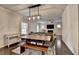 Open-concept dining area with modern light fixture flowing into living room with fireplace and television at 6468 Pierless Ave, Sugar Hill, GA 30518