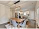 Open dining area featuring modern light fixture, wood table and grey upholstered chairs, flowing into the kitchen at 6468 Pierless Ave, Sugar Hill, GA 30518