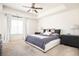 Bright main bedroom featuring large window, a tray ceiling with ceiling fan, and neutral decor at 875 Venture Sw Way, Atlanta, GA 30331