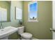 A half bathroom with green walls, a window, and a white toilet and sink at 518 Provence Gate Ln, Lawrenceville, GA 30044