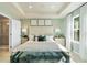 A spacious main bedroom featuring a tray ceiling, bedside tables, and a luxurious upholstered bed frame at 518 Provence Gate Ln, Lawrenceville, GA 30044
