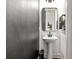 Stylish powder room with grey textured wallpaper, pedestal sink, and modern black accents at 2669 Caruso Way, Atlanta, GA 30339