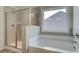 Bathroom featuring a drop-in tub and a separate shower with clear glass doors and gray tiled walls at 4534 Eastbrook Pl, Snellville, GA 30039