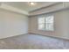 A spacious bedroom featuring neutral carpeting, a large window, a tray ceiling, and neutral-colored walls at 4534 Eastbrook Pl, Snellville, GA 30039