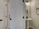 Compact powder room with pedestal sink, matte black fixtures, and decorative round mirror at 4659 Larkfield Way, Powder Springs, GA 30127