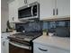 Close up of a modern kitchen with stainless steel appliances and black subway tile backsplash at 4659 Larkfield Way, Powder Springs, GA 30127