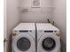 A laundry room with a modern front load washer and dryer units with folding rack above at 7979 Larksview Dr, Fairburn, GA 30213