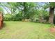Large, grassy backyard with a wooden fence, lush trees, and partial shade at 949 Hope Sw Dr, Atlanta, GA 30310