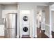 Bright laundry closet with stackable washer and dryer hidden behind bi-fold doors next to a stainless steel refrigerator at 949 Hope Sw Dr, Atlanta, GA 30310