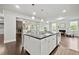 Open-concept kitchen island with white cabinets, dark counter tops, and dual living room fireplace view at 125 Registry Ln, Canton, GA 30115
