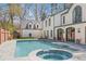 Backyard with a swimming pool and hot tub, surrounded by a gray-tiled patio and beautiful home exterior at 228 Mount Vernon Dr, Decatur, GA 30030
