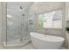 Bright bathroom showcasing a glass enclosed shower and modern soaking tub with natural light streaming through the window at 4294 Silver Peak Pkwy, Suwanee, GA 30024
