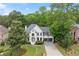 Wide angle view of a white brick two-story home with gray trim, a well manicured lawn and mature trees at 4294 Silver Peak Pkwy, Suwanee, GA 30024