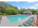 Community swimming pool with lounge chairs surrounded by lush greenery and mature trees for relaxation and recreation at 4294 Silver Peak Pkwy, Suwanee, GA 30024
