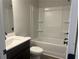 Bathroom with a dark vanity, sink, toilet, and a tub with shower at 4514 Eastbrook Pl, Snellville, GA 30039