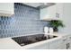 Close-up of modern kitchen with stylish backsplash, sleek cooktop, and white cabinetry at 4514 Eastbrook Pl, Snellville, GA 30039