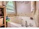 Large white bathtub with tile surround, window, and natural light at 95 Loudoun Dr, Covington, GA 30014