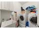 Functional laundry room with a utility sink, storage cabinets, and modern washer and dryer units at 2084 Democracy Dr, Buford, GA 30519
