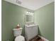 Powder room with a commode, vanity, and mirror on the green walls at 2084 Democracy Dr, Buford, GA 30519