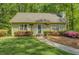 Charming one-story home features a lush green lawn, mature landscaping, and a welcoming walkway to the front door at 3957 Woodland Cir, Conyers, GA 30013