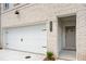 Attached garage and front entryway on a brick townhouse featuring a manicured lawn and landscaping at 4671 Larkfield Way, Powder Springs, GA 30127