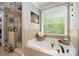 Relaxing bathroom featuring a soaking tub, walk-in glass shower, and large window with a wooded view at 507 Southshore Ln, Dallas, GA 30157