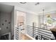 Bright hallway featuring modern railing, chandelier and view into a bedroom with stylish decor and natural light at 507 Southshore Ln, Dallas, GA 30157