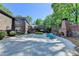 Expansive brick patio with outdoor fireplace, and brick retaining wall, surrounded by greenery and lush trees at 168 Woodland Valley Rd, Lawrenceville, GA 30046