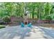 Backyard with brick fireplace and retaining wall, offering a private outdoor space with mature trees at 168 Woodland Valley Rd, Lawrenceville, GA 30046