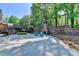 Large concrete backyard patio area featuring a brick fireplace and two chairs at 168 Woodland Valley Rd, Lawrenceville, GA 30046