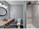 Updated bathroom featuring a vanity with a unique sink, dark fixtures, a round mirror, and an elegant tiled shower at 168 Woodland Valley Rd, Lawrenceville, GA 30046