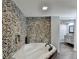 Bathroom featuring tub with stone accent wall, faucet, and view to granite sink and wood tile floors at 168 Woodland Valley Rd, Lawrenceville, GA 30046