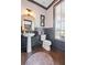 Charming powder room featuring pedestal sink, decorative wallpaper, and dark wood trim and hardwood floors at 214 Bluestone Dr, Woodstock, GA 30188