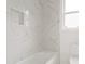 Modern bathroom showcasing marble-style tile, a built-in niche, and a soaking tub under a window at 1525 Tapestry Rdg, Lawrenceville, GA 30045