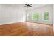 Spacious bedroom with hardwood floors, large windows, decorative wall paneling, and a modern ceiling fan at 1525 Tapestry Rdg, Lawrenceville, GA 30045