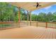 Large covered porch with wood floors, ceiling fan, iron railings, and views of the backyard trees at 1525 Tapestry Rdg, Lawrenceville, GA 30045