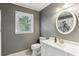 Neutral bathroom features a window, toilet, single vanity with a white countertop and oval mirror at 3322 Woodsfield Ne Dr, Marietta, GA 30062