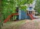 Exterior view of blue home featuring multiple decks with staircases and nestled in a lush, wooded landscape at 1310 Ridgeview Rd, Auburn, GA 30011